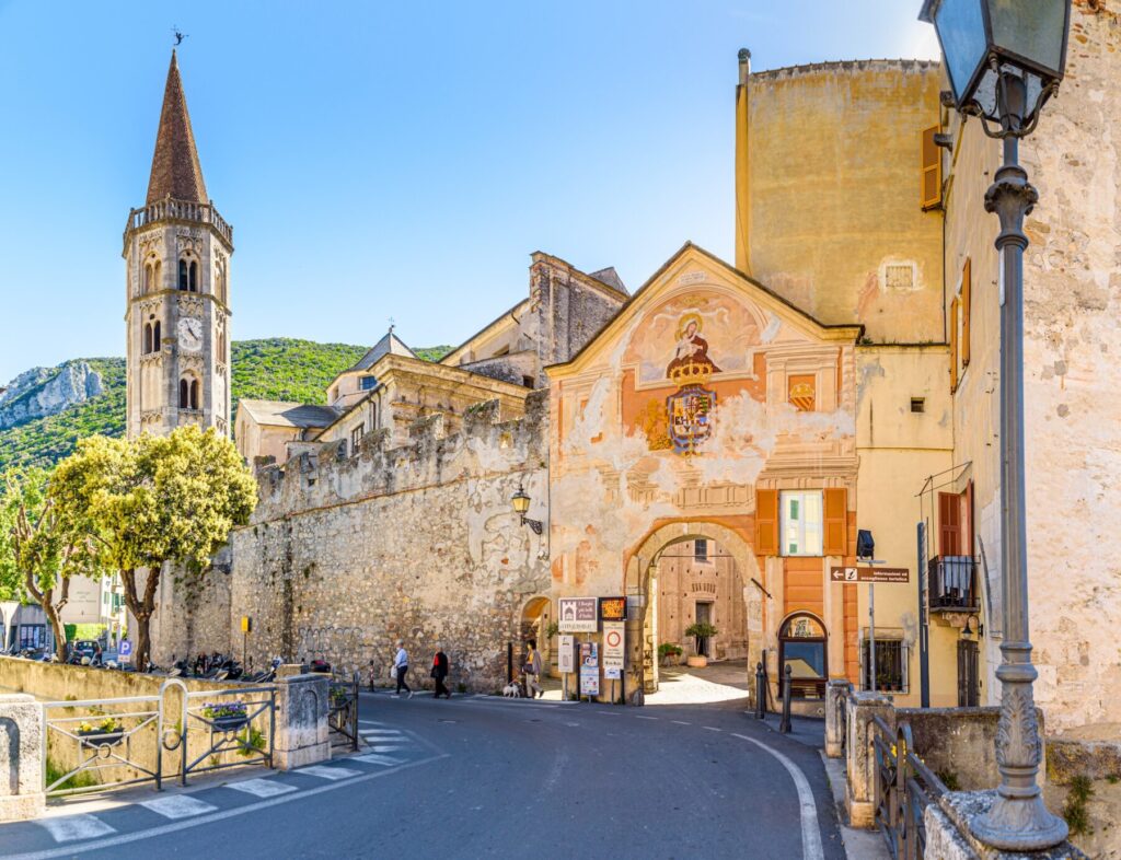 Finalborgo, Finale Ligure, Italy. May 5, 2021. View of the external facade of Porta Reale and of the ancient walls with the bell tower of the Church of San Biagio on the left.